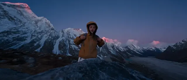 Traveler wearing an orange jacket in a wide view of snowy mountain peaks